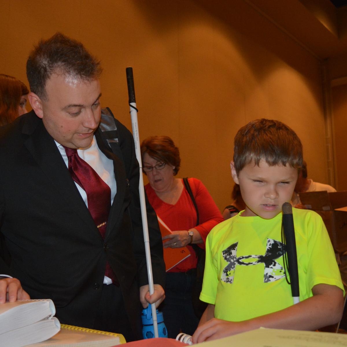 a young blind boy talking to NFB president Mark Riccobonno