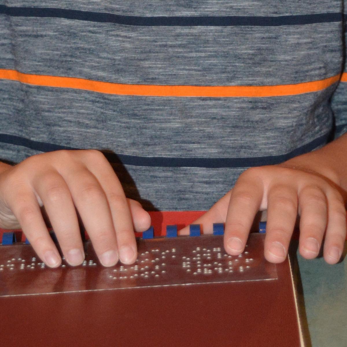 small child hands reading braille