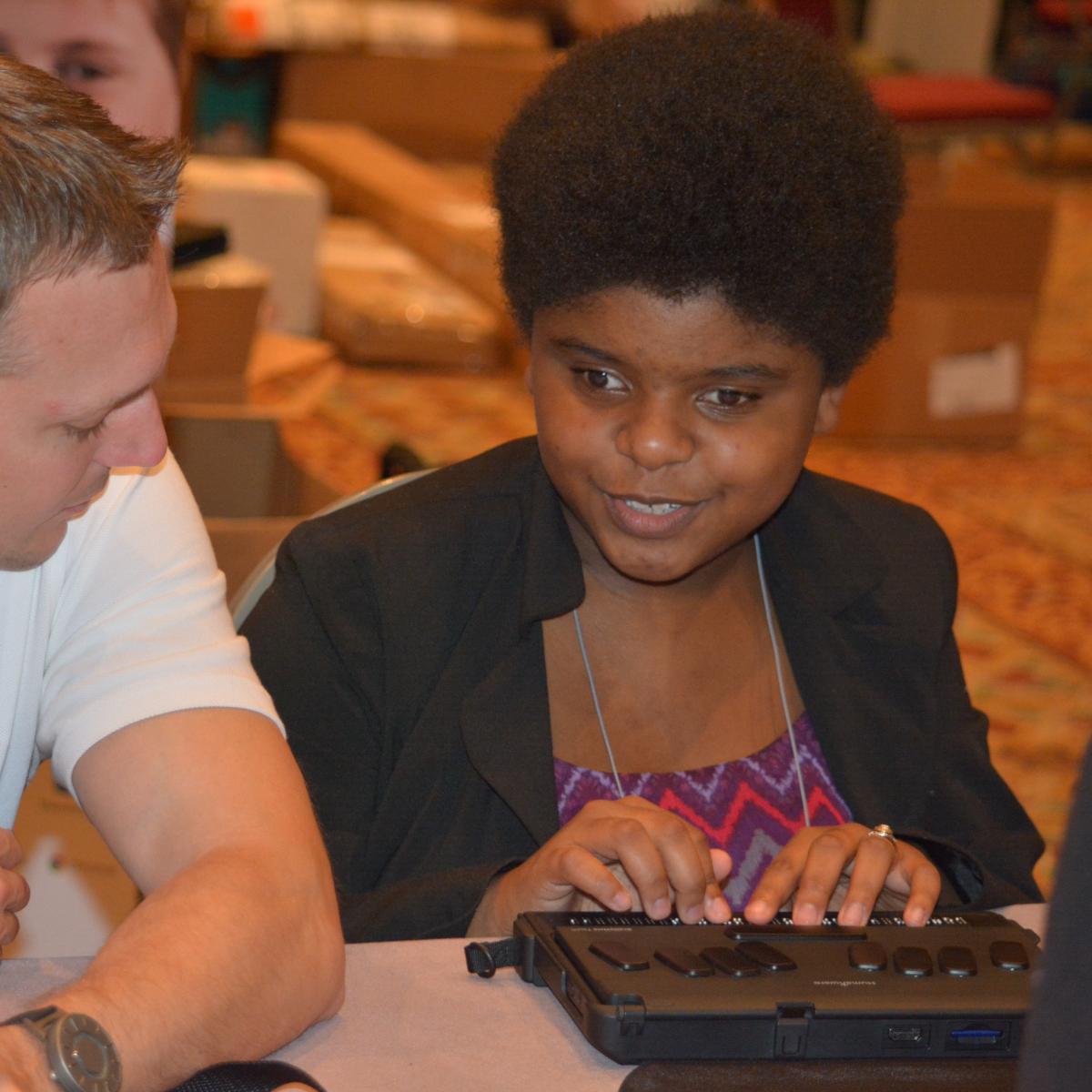 a young woman uses a braille notetaker device